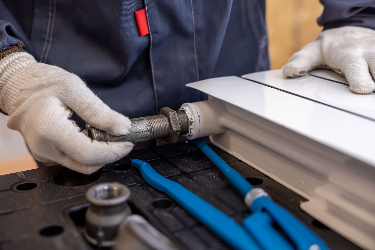 our-story Close-up of a plumber installing a radiator pipe using specialized tools.